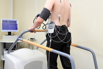 Patient with ECG electrodes on back and an instrument for measuring blood pressure during exercise on treadmil