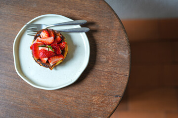 Top of delicious strawberry cheesecake in plate on wooden table, flat lay food concept.