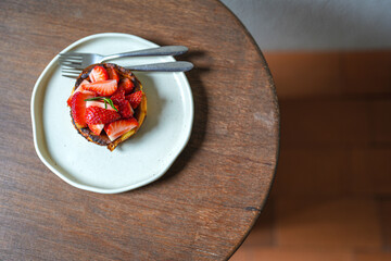 Top of delicious strawberry cheesecake in plate on wooden table, flat lay food concept.