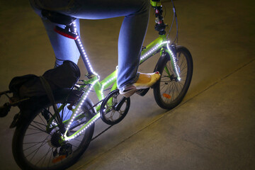 Female feet pedal bicycle with backlight in the dark