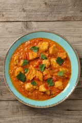 Delicious chicken curry on wooden table, top view