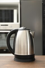 Modern electric kettle on table in kitchen