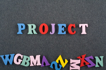 PROJECT word on black board background composed from colorful abc alphabet block wooden letters, copy space for ad text. Learning english concept.