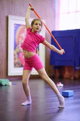 Foto op Plexiglas Girl in pink dances with red sport stick in gym hall, shallow dof © Pavel Losevsky
