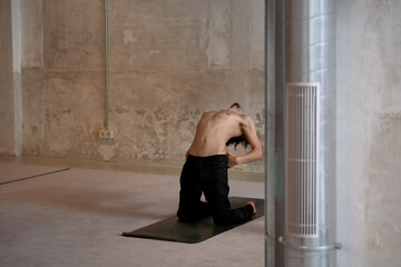 Shirtless man doing Supported Camel pose in studio