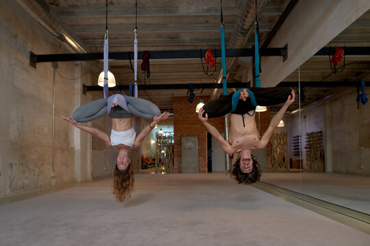 Man and woman doing aerial yoga on hammocks