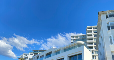 Contemporary white buildings with balconies against a blue sky. Part of architectural structures.