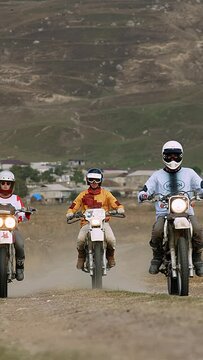 The image showcases three motorcyclists, united by their passion for speed and adventure, as they navigate a dusty, winding mountain track. The dynamic scene is set against a rugged landscape, where