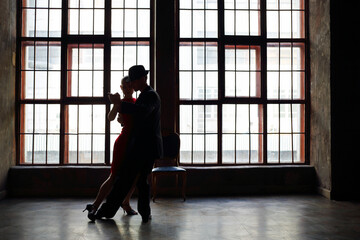 Silhouette of girl in red dress and man in black suit dancing tango