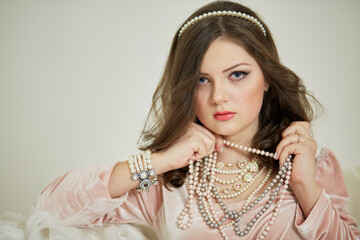 Young woman in pink dress with pearl necklace and diadem in hair.