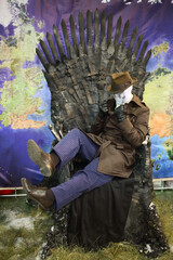  Cosplay Rorschach in the white mask and hat sitting on a brown coat black throne at the EveryCon...