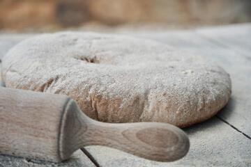 Bread with flour and rolling pin to knead on a rustic white wooden table. 