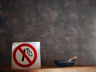 Smoking cigarette in front of no smoking sign