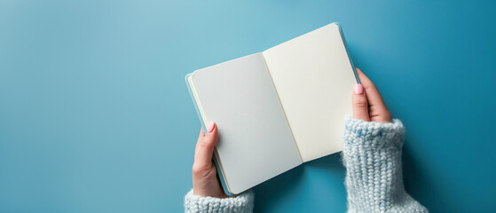 Female hand holding an open notebook on a light blue background. Top view generate ai