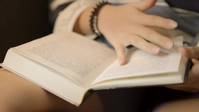 teenage girl, comfortably seated on sofa,is engrossed in the pages of a book, her attention completely captured by the story as she immerses herself in a world of imagination and literature.