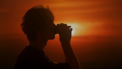Silhouette of a man drinking coffee at sunset