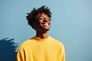 Man in yellow experiencing pure joy, against a calming blue background. - obrazy, fototapety, plakaty