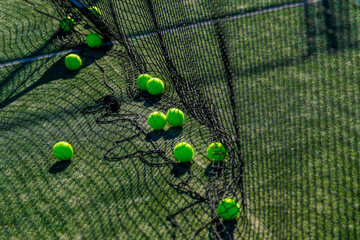 Bright tennis balls on green court, caught in the net