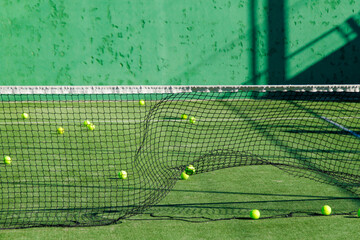 Vibrant green padel court with yellow balls and artistic shadows, perfect for sports lovers