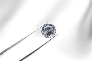 Tweezers with beautiful shiny diamond on light background, closeup