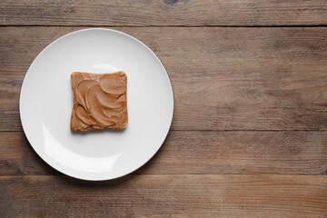 Toast with tasty nut butter on wooden table, top view. Space for text