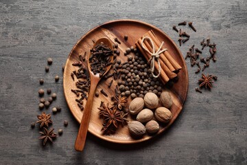 Different spices and nuts on gray textured table, top view