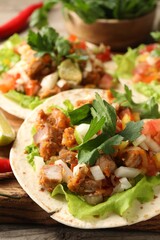 Delicious tacos with vegetables and meat on table, closeup
