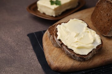 Slices of tasty bread with butter on grey textured table, closeup. Space for text