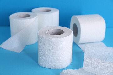 Soft toilet paper rolls on light blue background, closeup