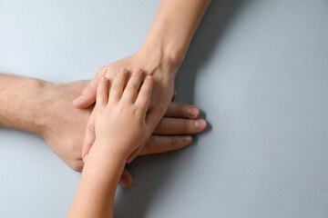 Parents and child holding hands together on gray background, top view. Space for text