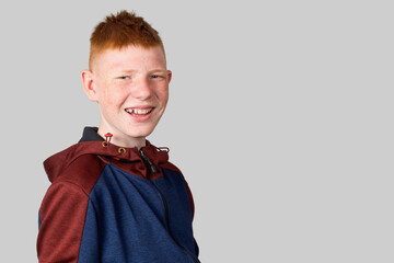 A teenager with red hair looks at the camera, grimaces and smiles evilly.