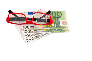 glasses with broken optical vision on top of money in 100 bills