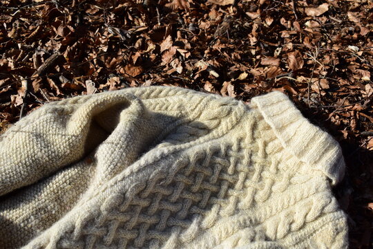 Pullover mit Zopfmuster in naturwei&szlig;er Schafwolle als Hintergrund