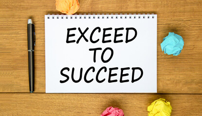 Exceed to succeed symbol. Concept words Exceed to succeed on beautiful white note. Beautiful wooden background. Black pen. Colored paper. Business and exceed to succeed concept. Copy space.