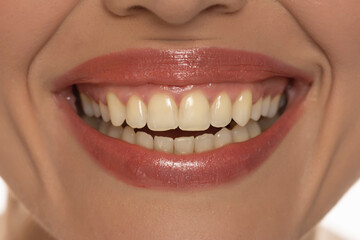 Close-up of a woman's mouth, capturing a confident smile and perfect natural teeth and lips