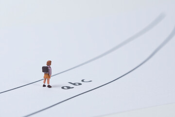 ein Schulkind steht auf einer Straße wo die Buchstaben a b c geschrieben sind, Fotografie von miniatur figuren - obrazy, fototapety, plakaty