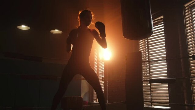 Women self defense girl power. Strong woman fighter training punches on boxing ring. Healthy strong girl punching boxing bag. Training day in boxing gym. Strength fit body workout training