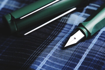 Fountain pen with cap on checkered fabric background.