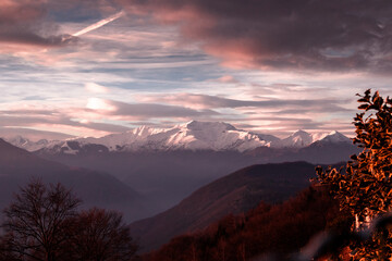 Snowed mountains, with colorful glowing clouds. Sunset over the snowed mountains. Monte Massone seen from Armeno. Piedmont - Italy.
