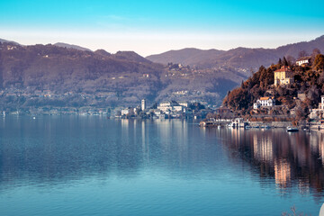 Fototapeta na wymiar San Giulio Island in a dreamy light of winter and water reflection - Lake Orta, Italy