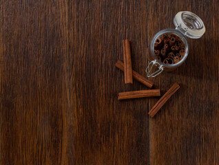 cinnamon sticks in a glass jar on a dark wooden table , top view.