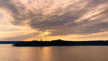 Naklejka premium Orange sunset sky over island with lighthouse