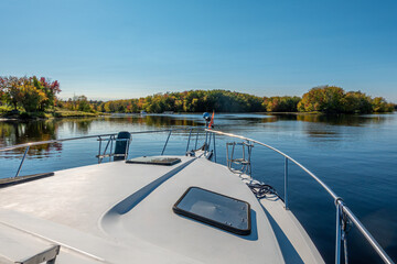 Looking out over the bow of a boat at a beautiful river and fall foliage