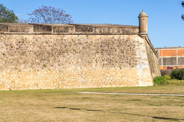 Sentinel Vigilance: Bastioned wall with tower and green garden.