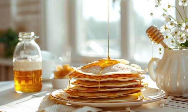 Pankakes on the plate poured with honey on decorated table in modern white kitchen with daylight