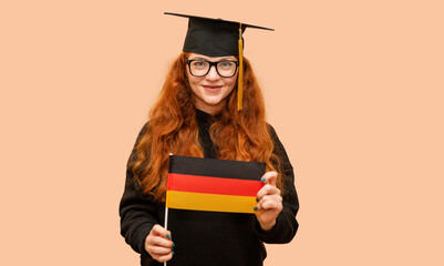Female graduate student with German flag and bachelor's cap standing on pink background.