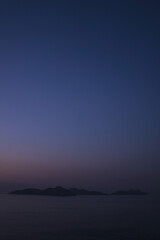 Tranquil seas and the stunning silhouette of Cies Islands against a backdrop of the orange that remains from sunset and deep blue in the sky during the magical blue hour at Monteferro.