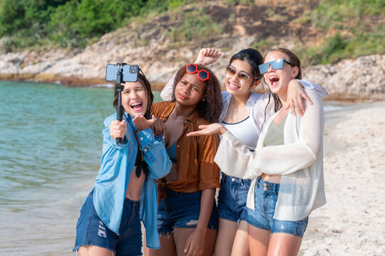 Group of diverse young women taking a selfie with a smartphone on a sunny beach day. Friends Taking Selfie at Beachside.