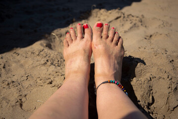 Pies de mujer con uñas rojas en la arena