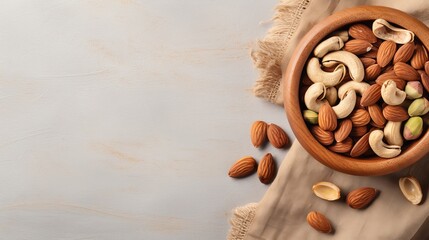 Almonds, pistachios, and cashews arranged in a wooden bowl on a linen napkin, set against a light grey background. (Horizontal view with space for text) - obrazy, fototapety, plakaty